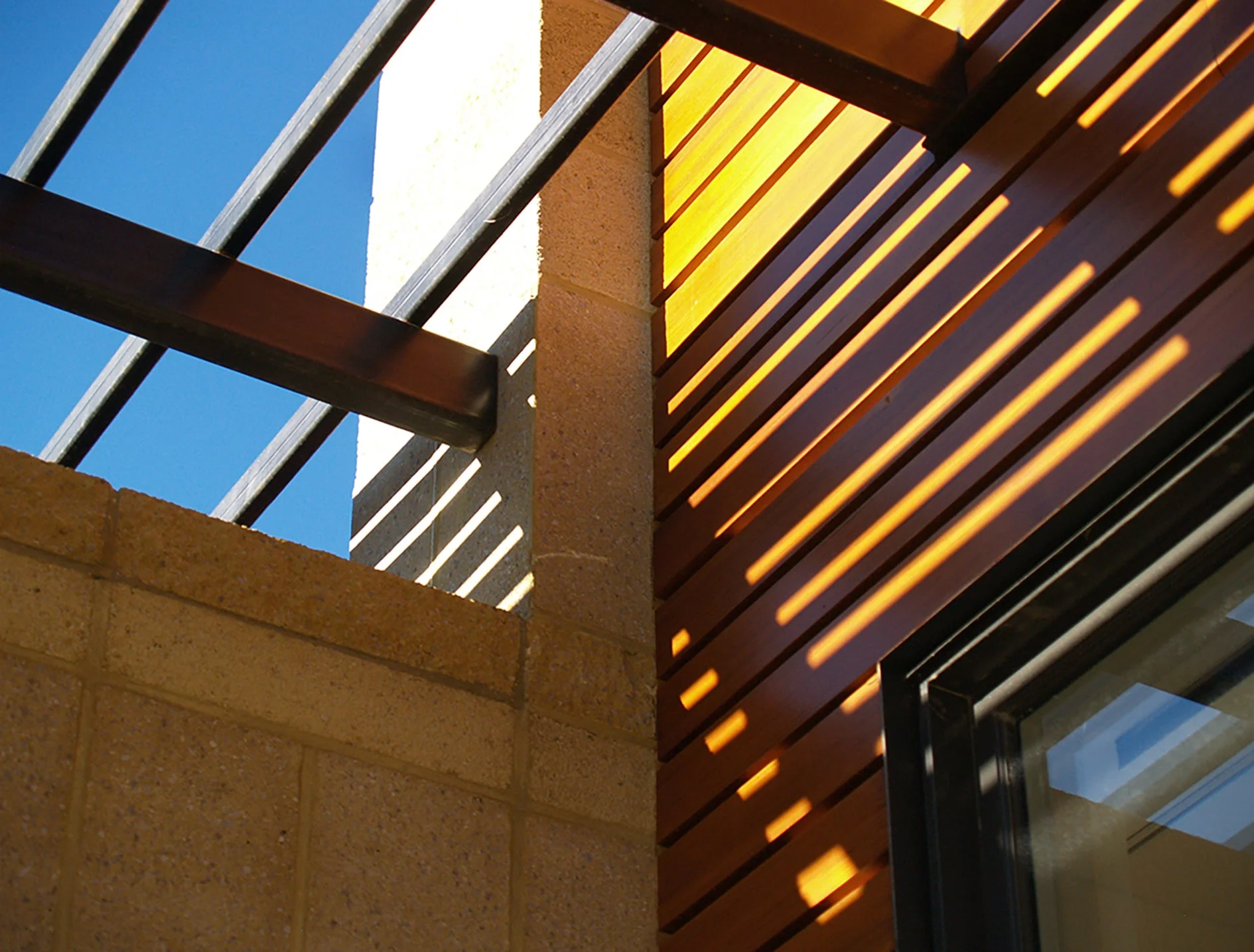 Trellis shadows striping cedar siding and block walls