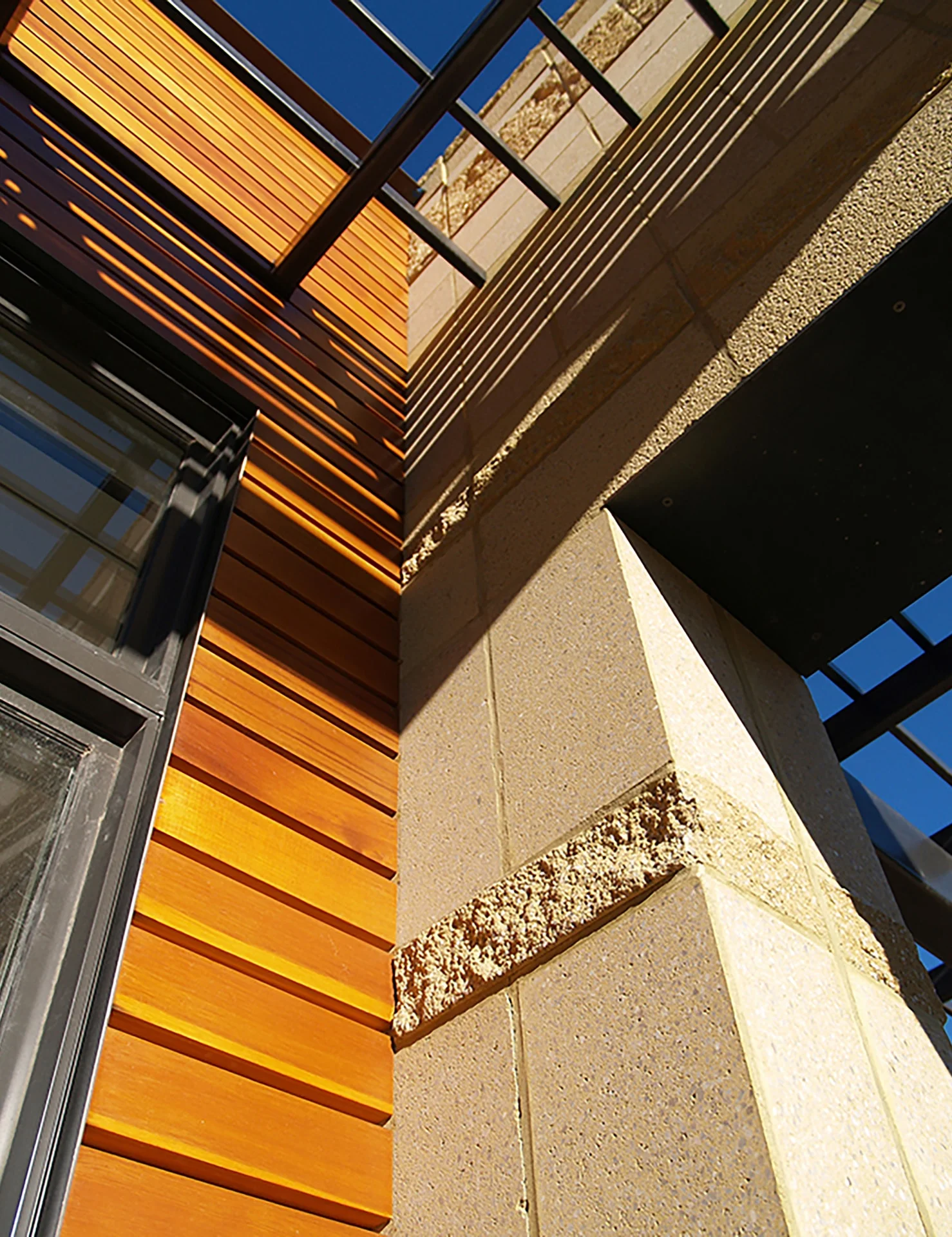 Cedar siding meeting rough-faced block and steel window frames