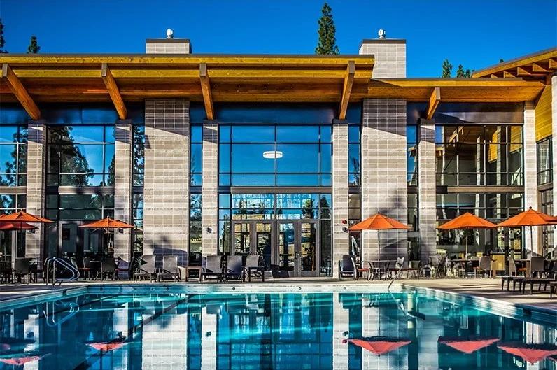 Pool and umbrellas in front of the glass and masonry facade