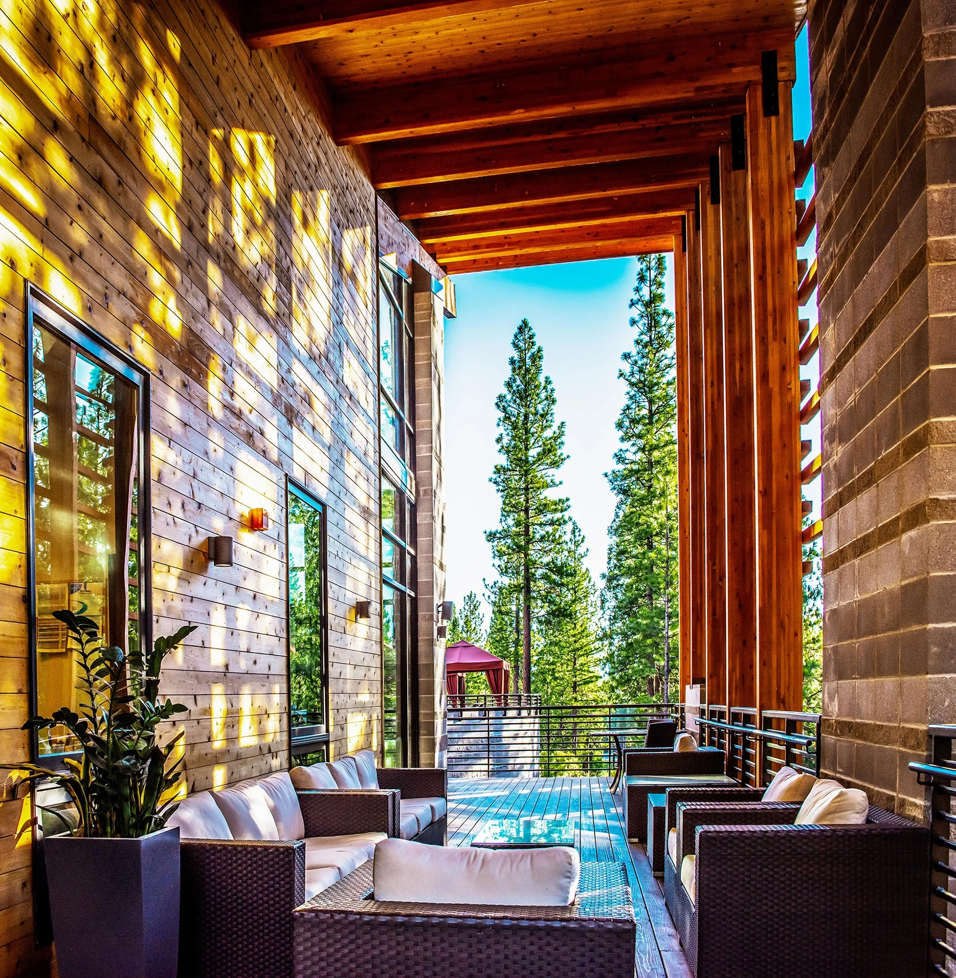 Covered terrace with lounge seating between masonry and timber columns overlooking the pool
