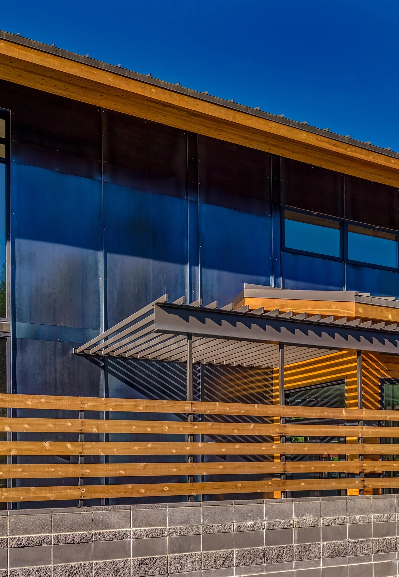 Horizontal wood slats and dark metal panels beneath a shed roof
