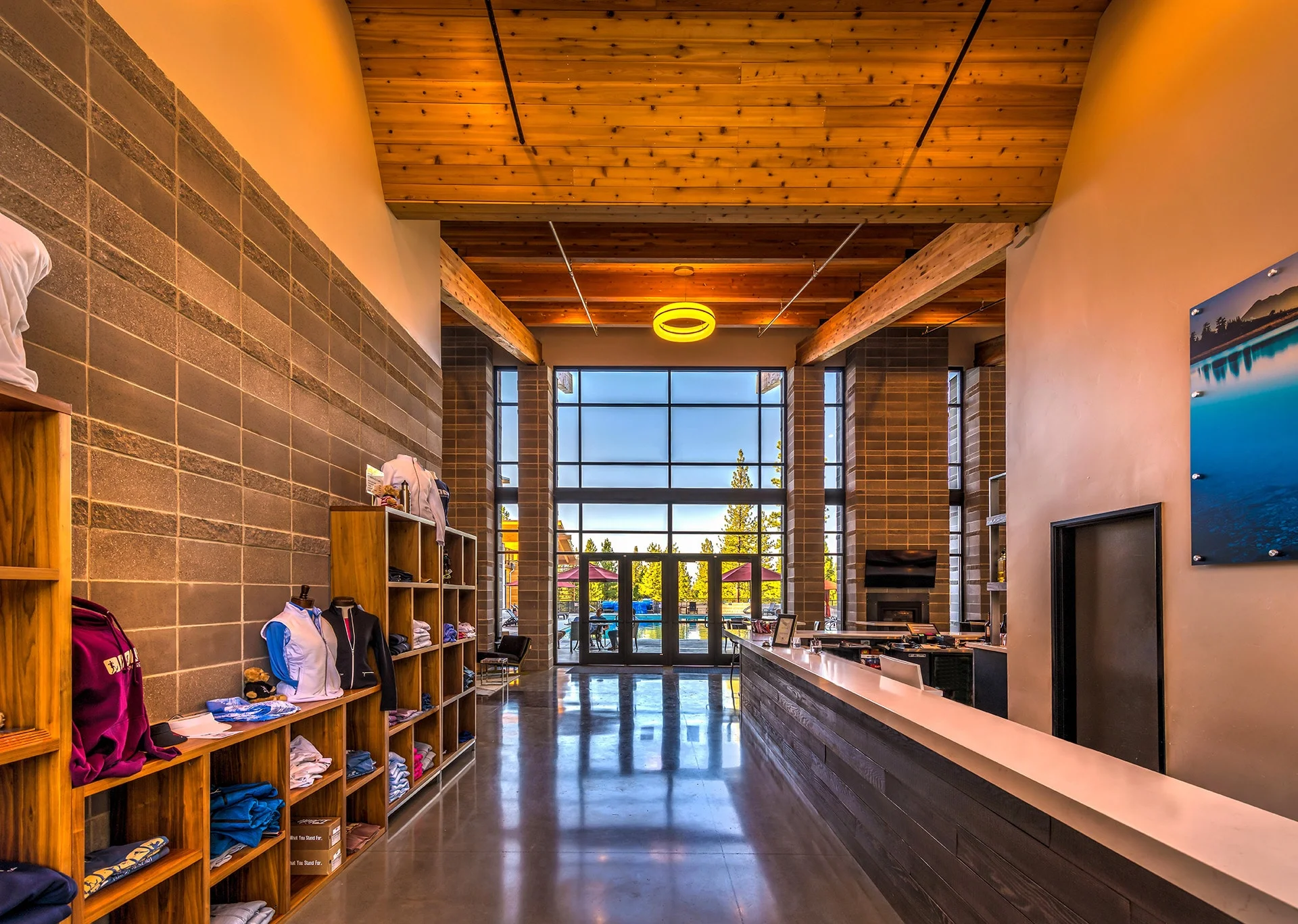 Reception and retail counter beneath a wood ceiling with views out to the trees