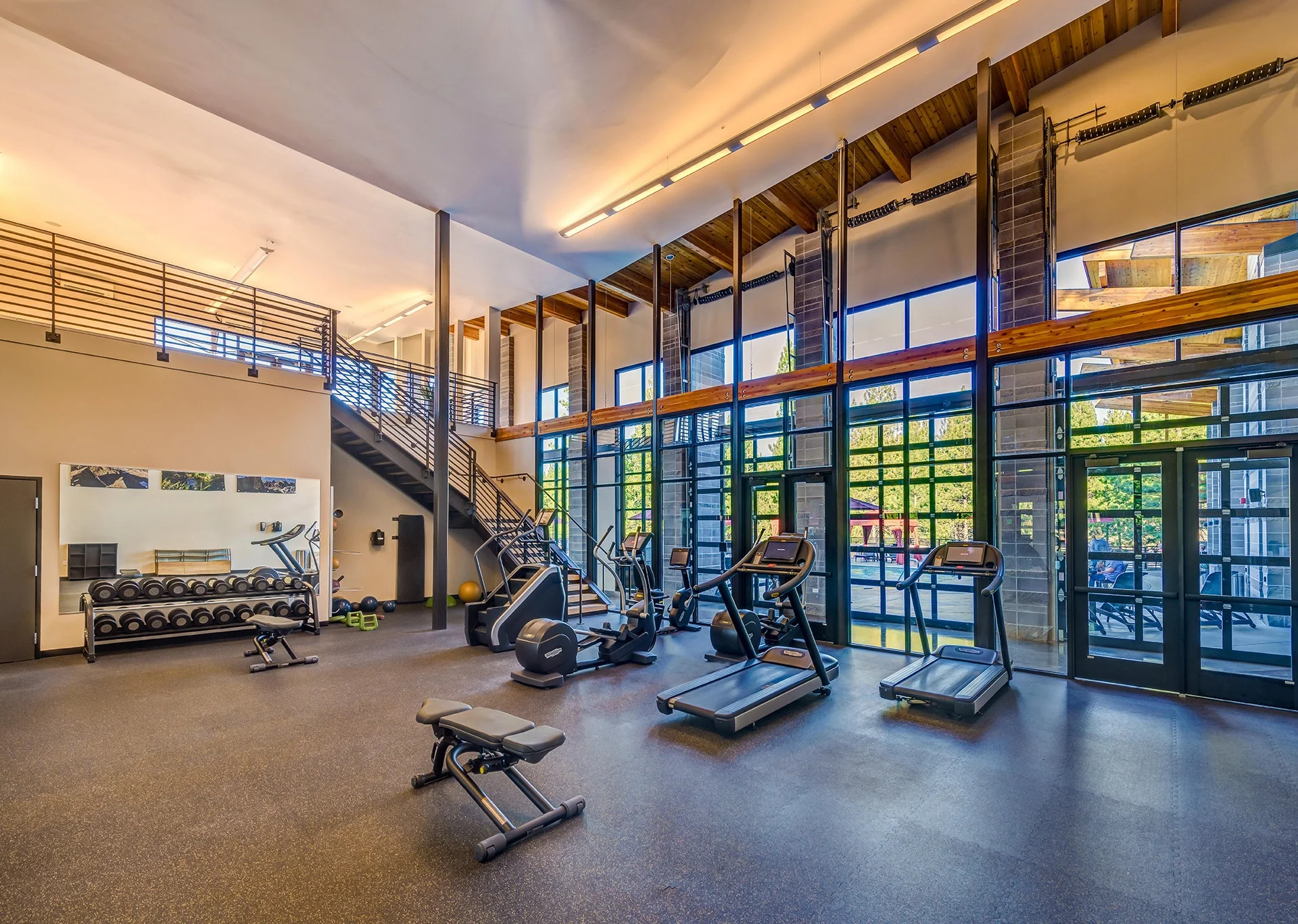 Fitness center with treadmills and bikes facing a two-story window wall