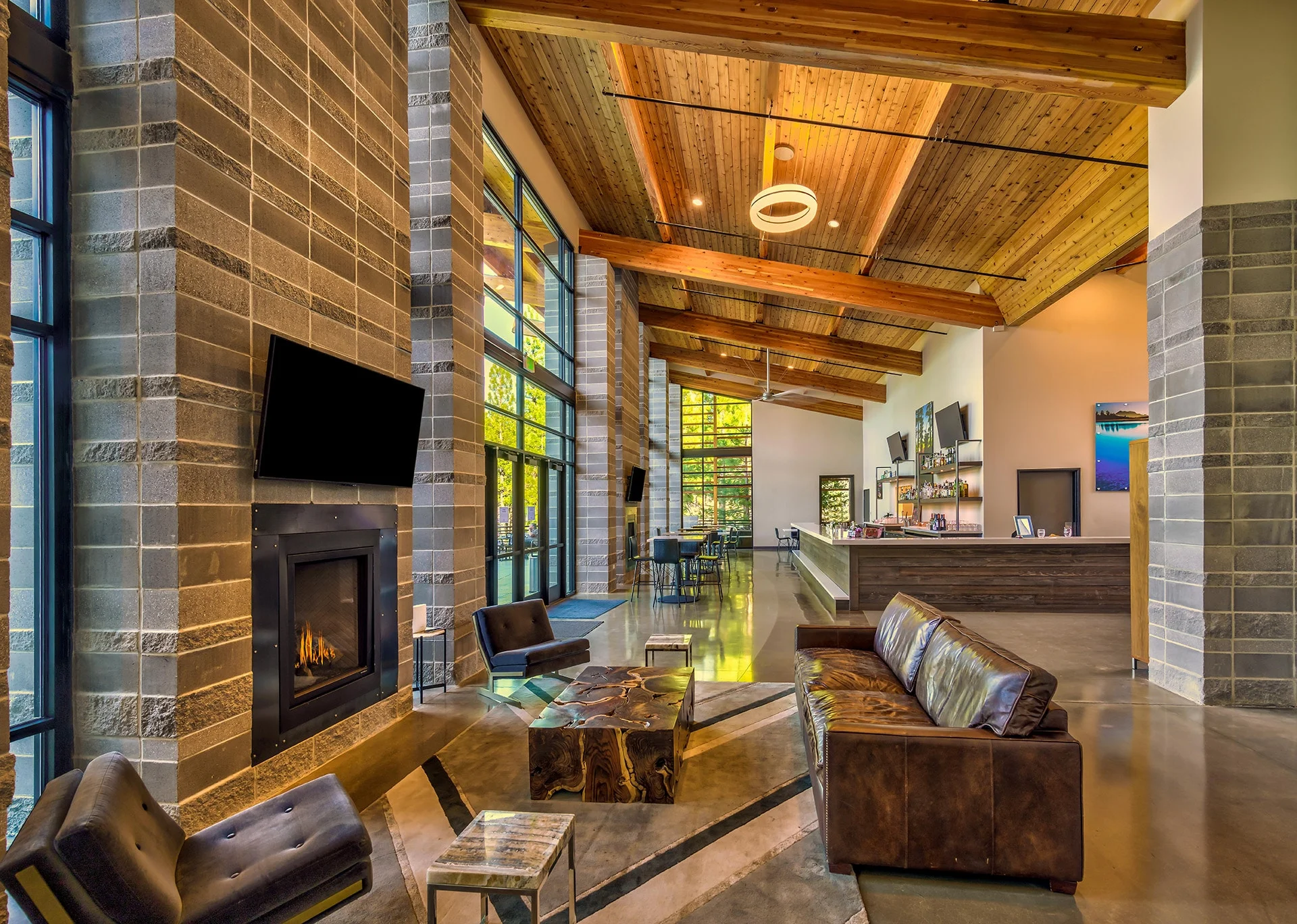 Lounge with a stone fireplace, leather seating, and a wood ceiling