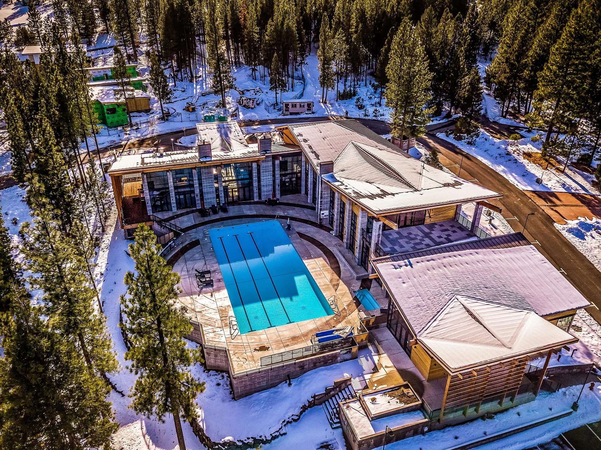 Aerial view of the pool and roofs surrounded by snowy forest