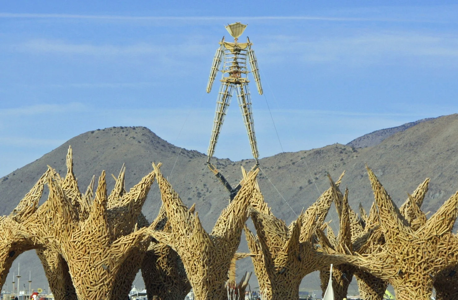 The finished Man rising above sculptural spires with mountains behind