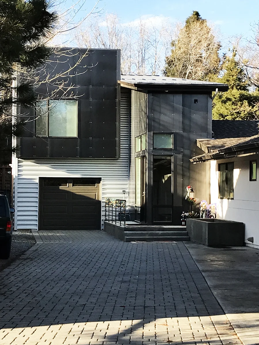 Front of the renovated home with the new foyer and dark metal second floor above the garage