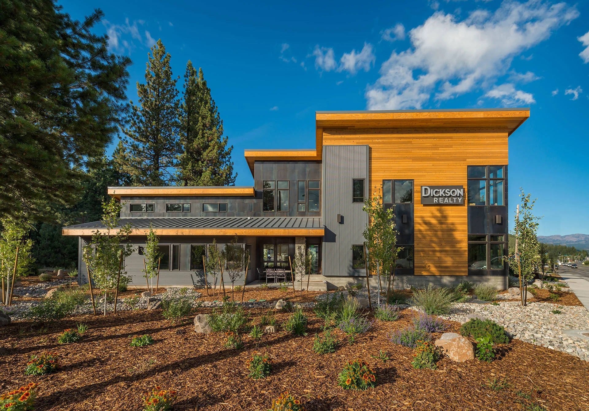Dickson Realty building with cedar and dark metal siding, upswept roofs, and native landscaping