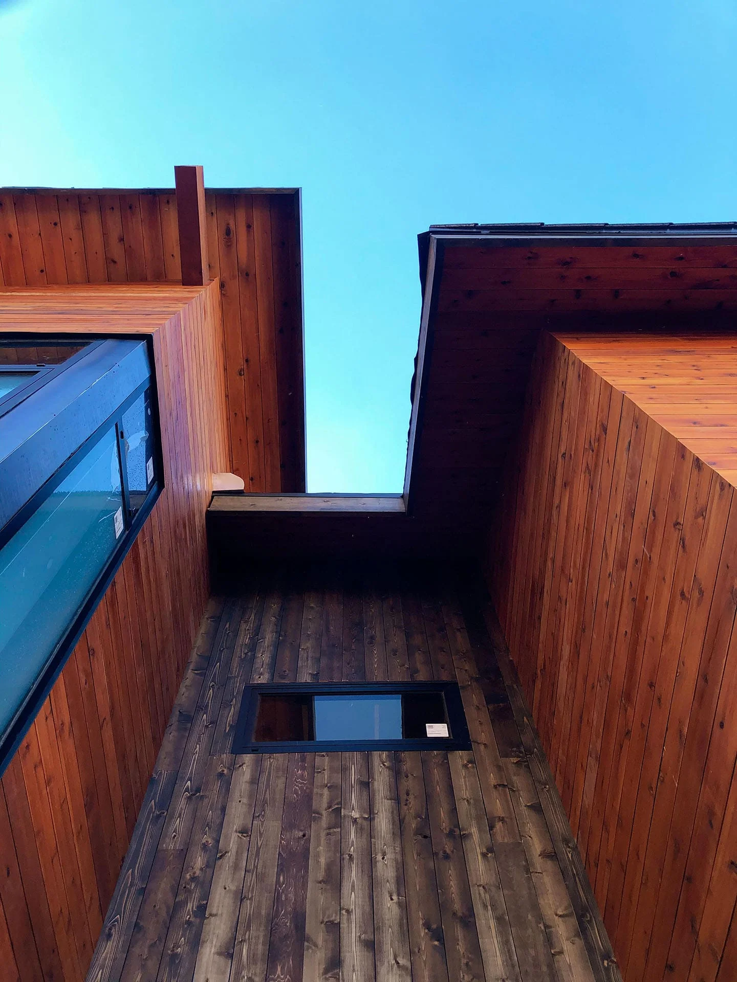 Cedar-clad corner of the house with a tall window