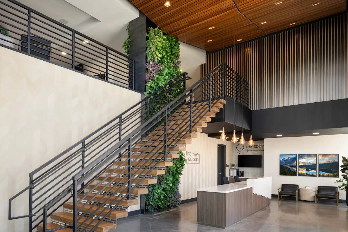 Open steel stair with wood treads beside a living green wall in the entry