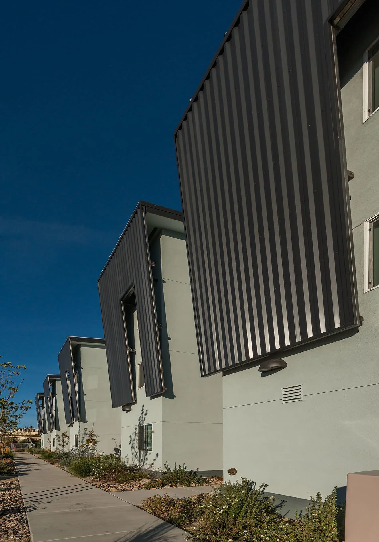 Row of metal-clad bays along the sidewalk under a deep blue sky