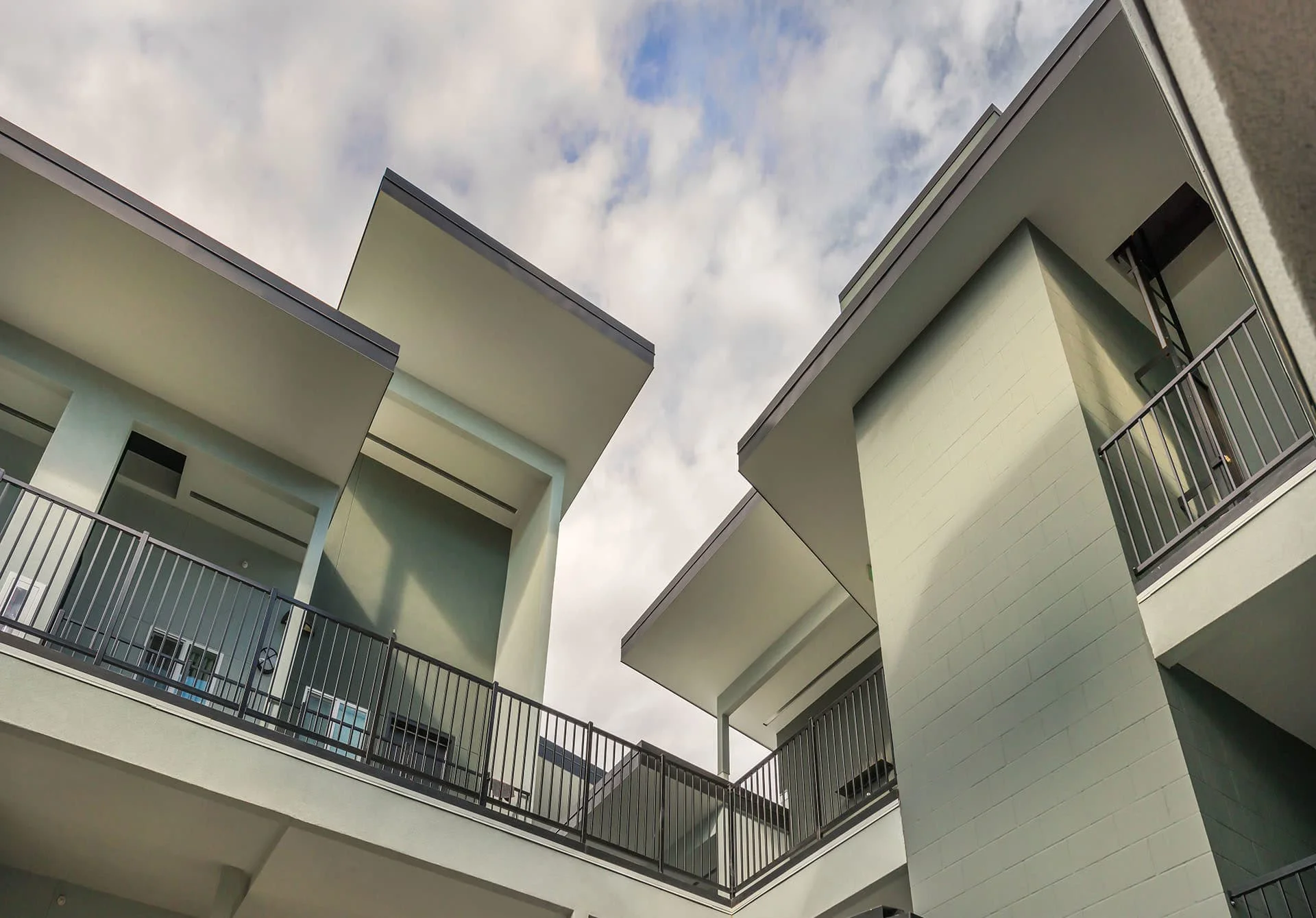 Angled roof planes and balconies against a cloudy sky