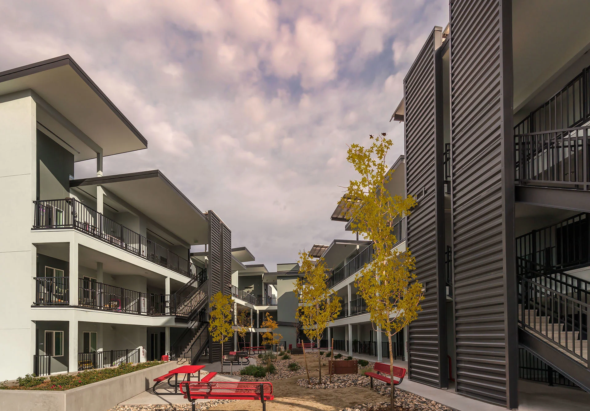 Courtyard between apartment wings with walkways, metal stair towers, and young trees