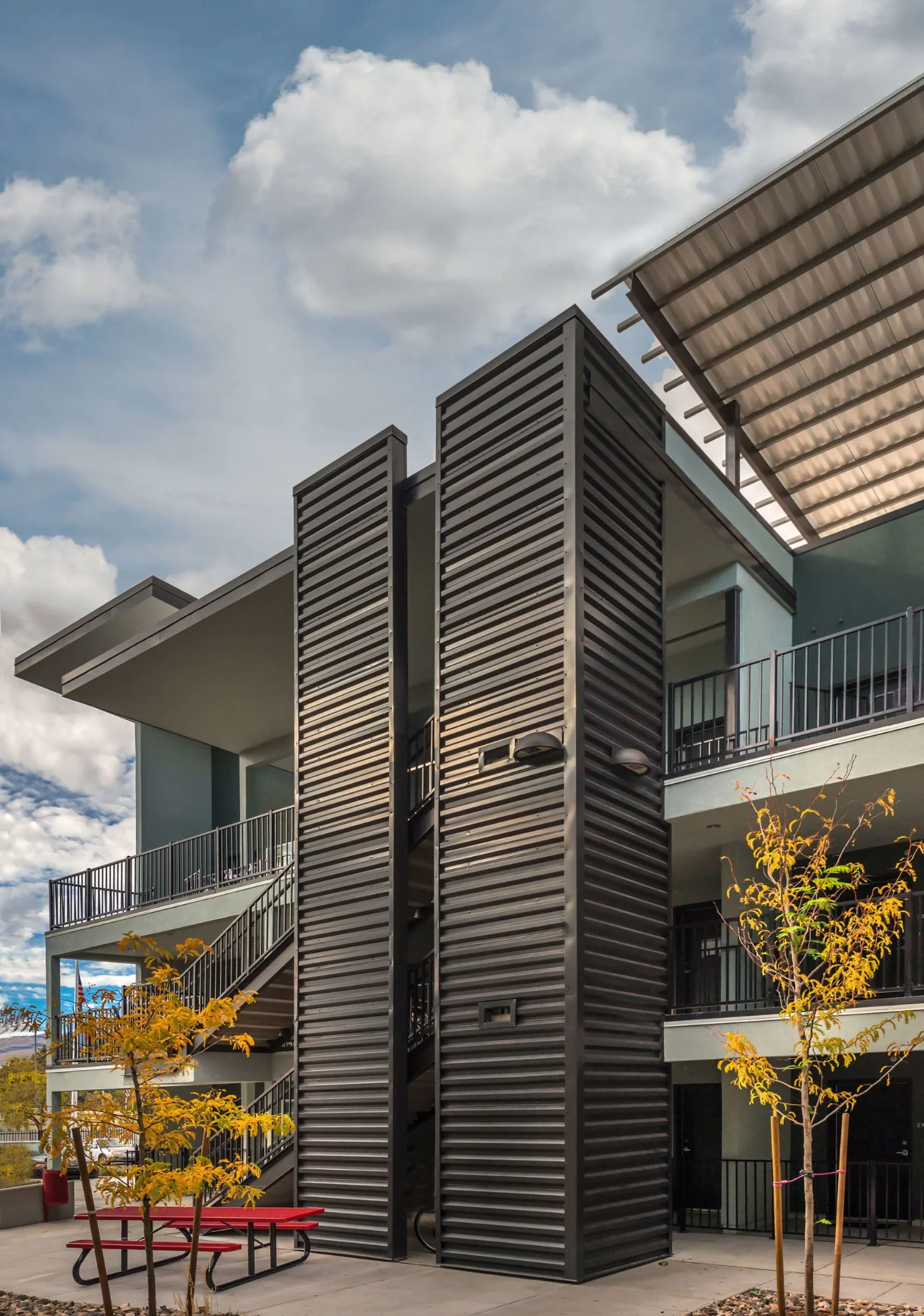 Corrugated metal stair tower with an angled canopy above a red picnic table