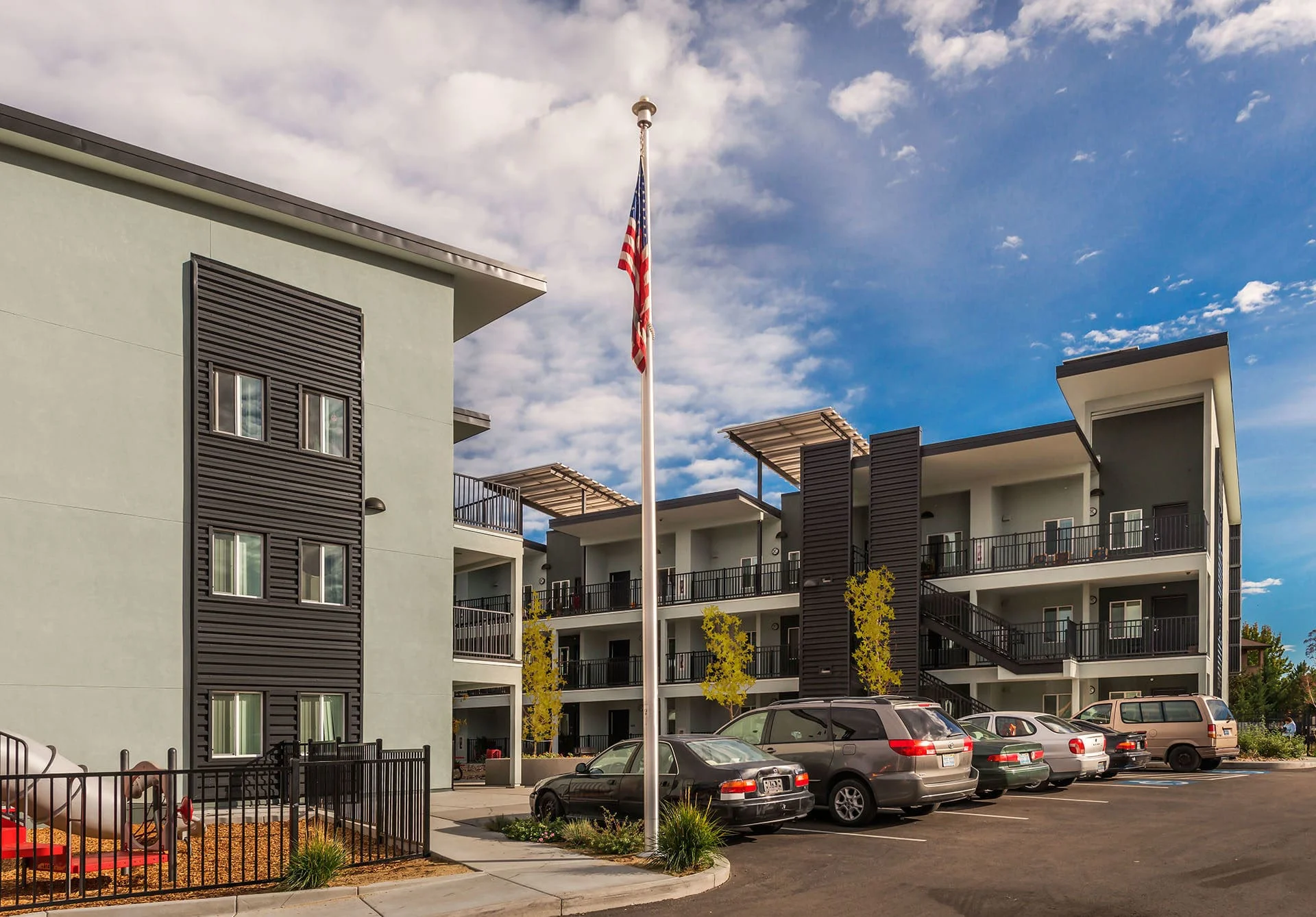 Apartment buildings, parking, and flagpole with the community center beyond