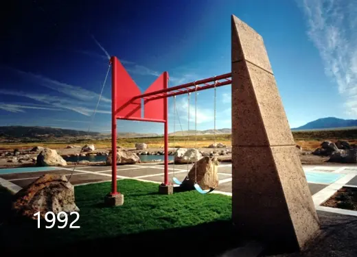 Red steel frame beside a leaning concrete panel against a deep blue sky, photographed in 1992
