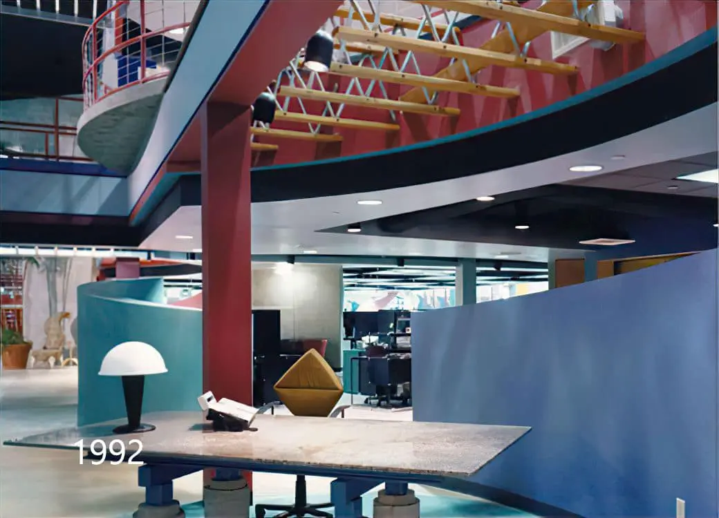 Open office with a red column, curved blue partition, and sculptural desk, photographed in 1992