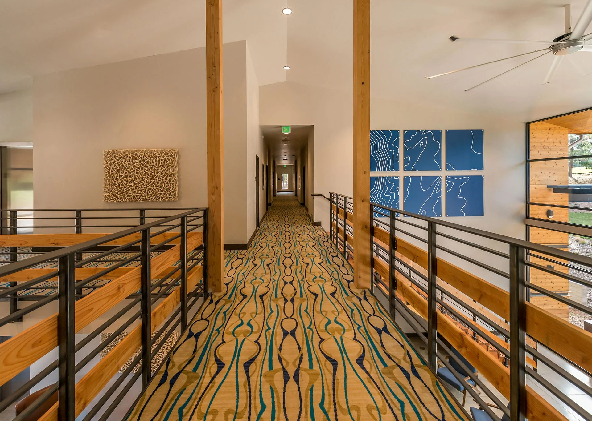 Upper corridor with patterned carpet and wood and steel railings