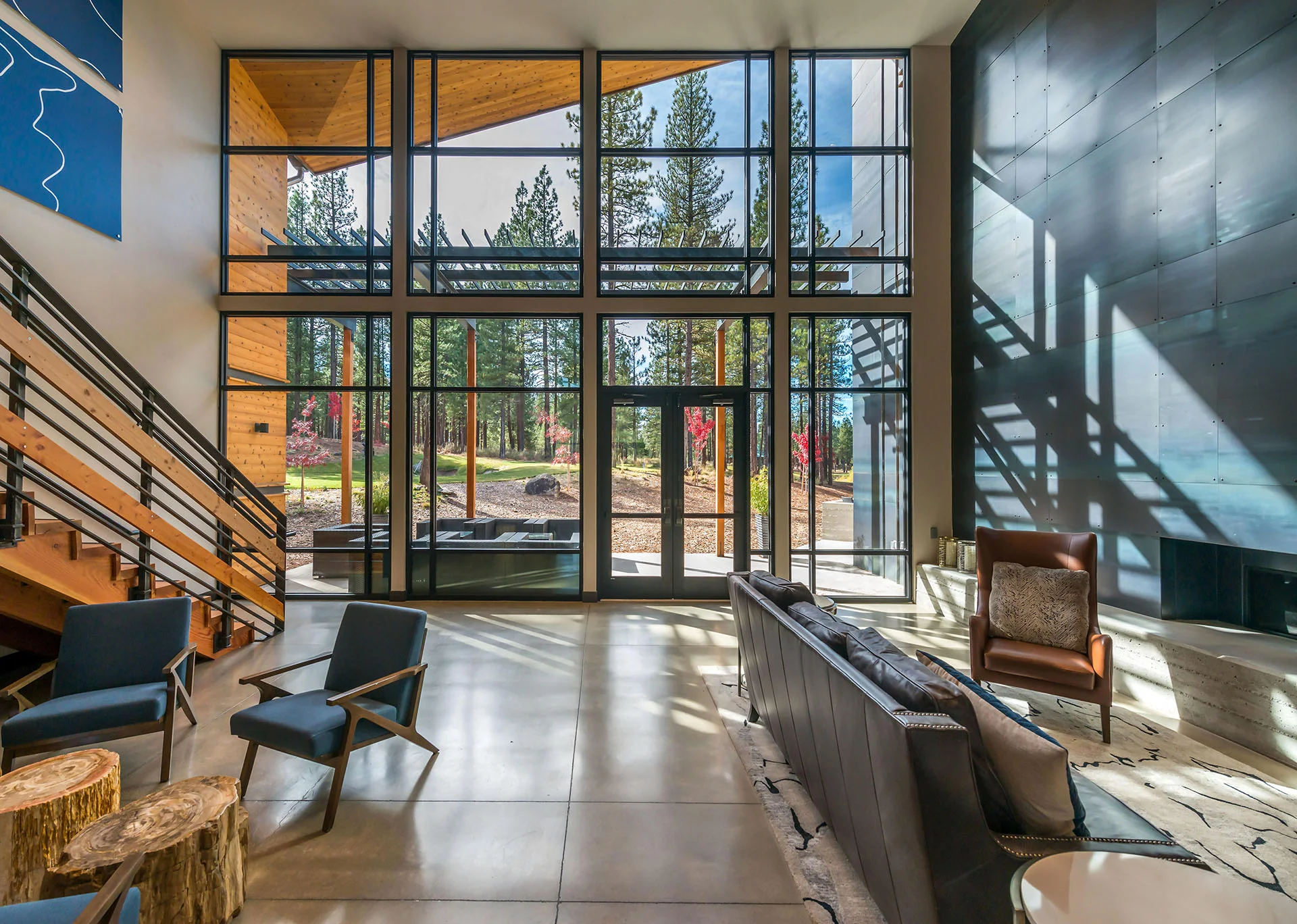 Lobby seating in front of a two-story window wall looking out to the pines