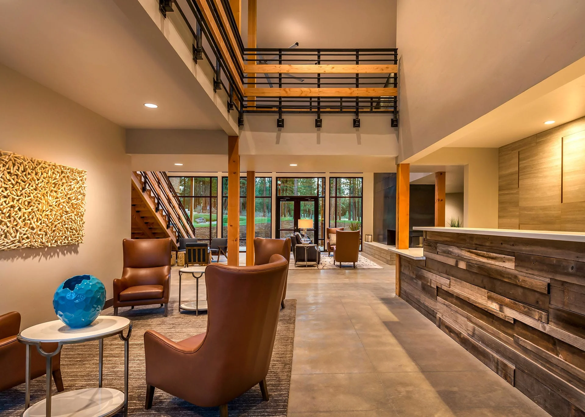 Reception desk of reclaimed wood with lounge chairs and a stair to the mezzanine