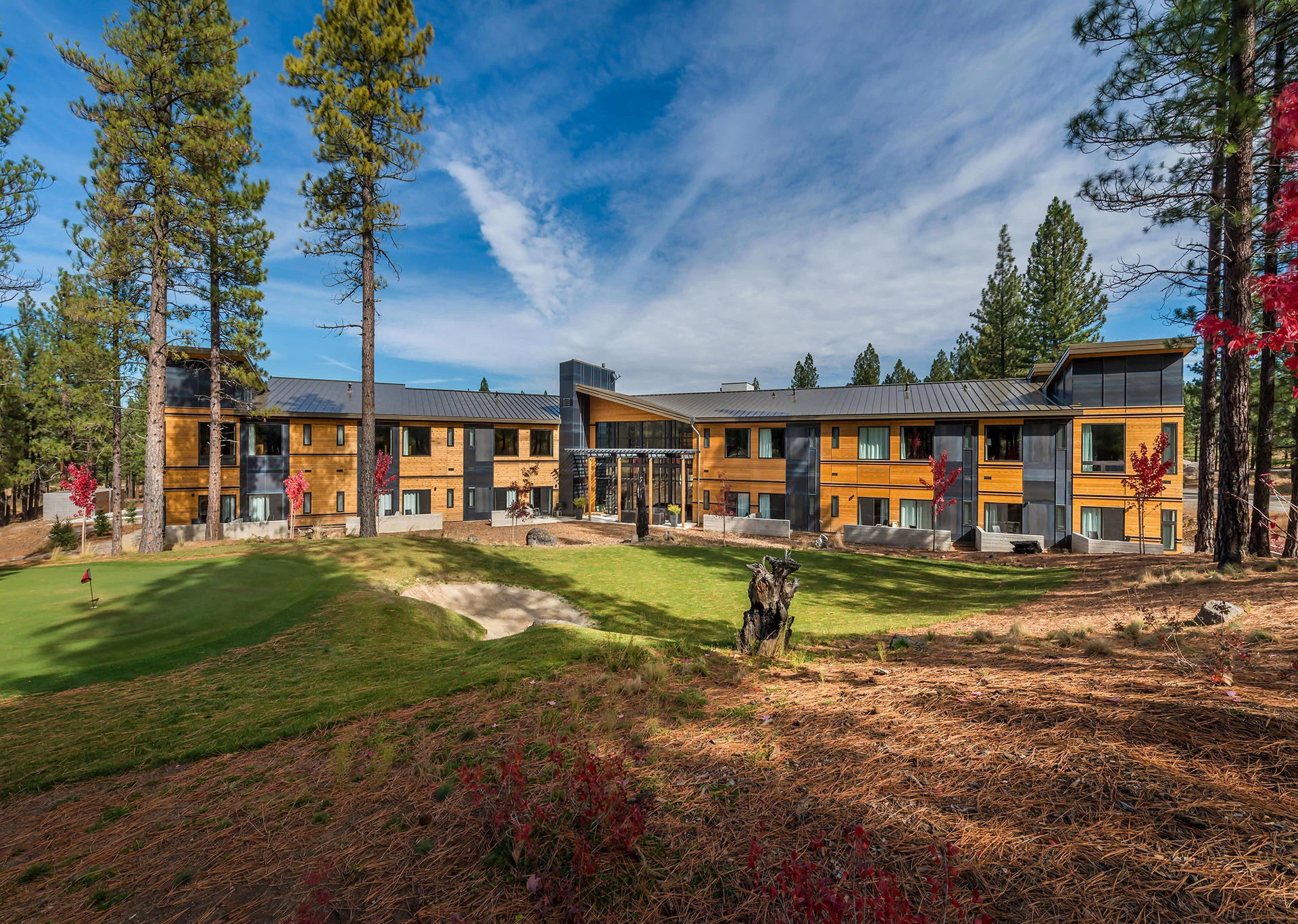Long low lodge wings across a wide lawn and pines
