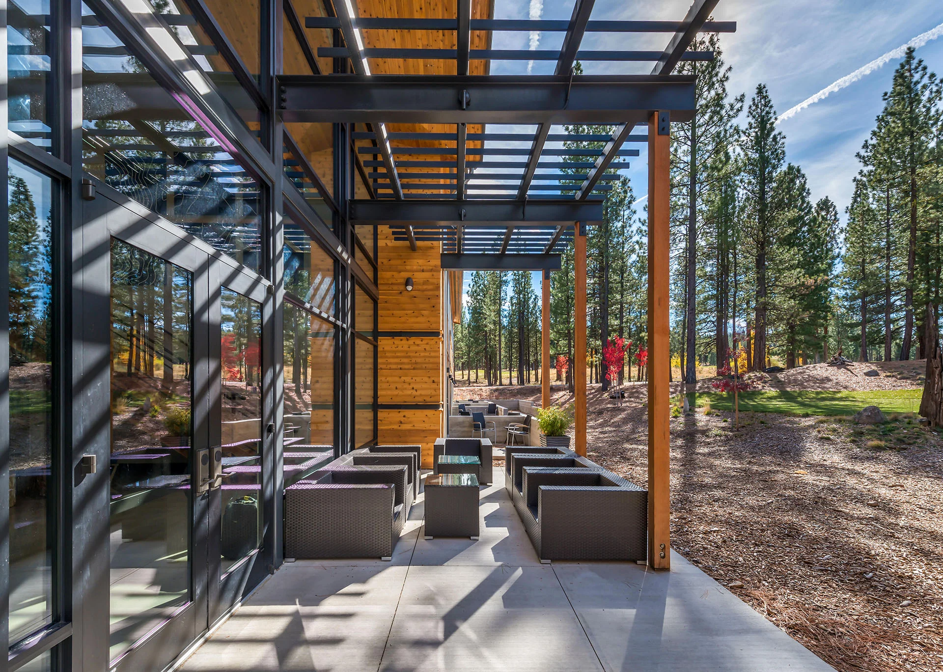 Covered outdoor terrace with steel and wood trellis framing lounge seating