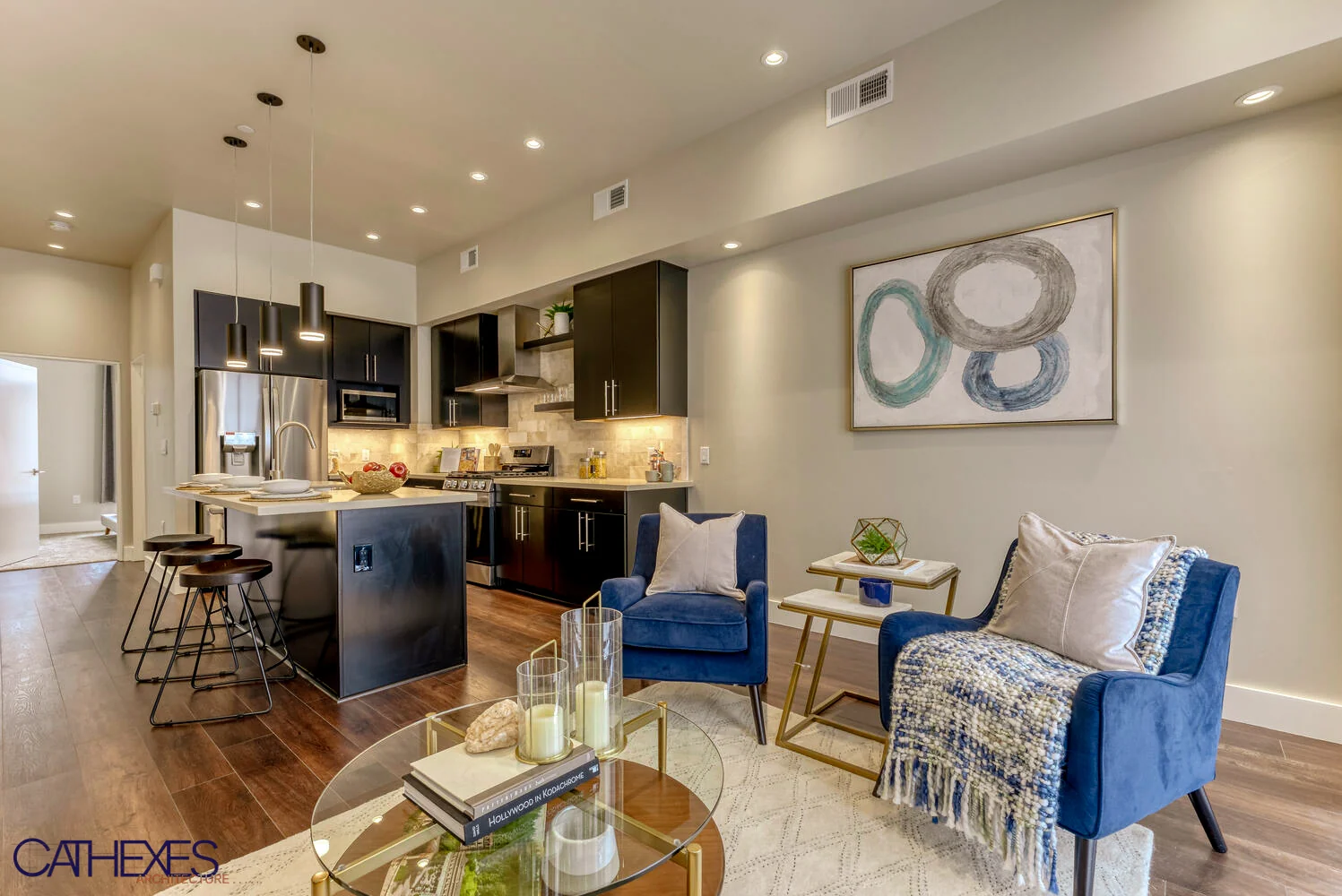 Open living room and kitchen with dark cabinets, an island, and blue armchairs