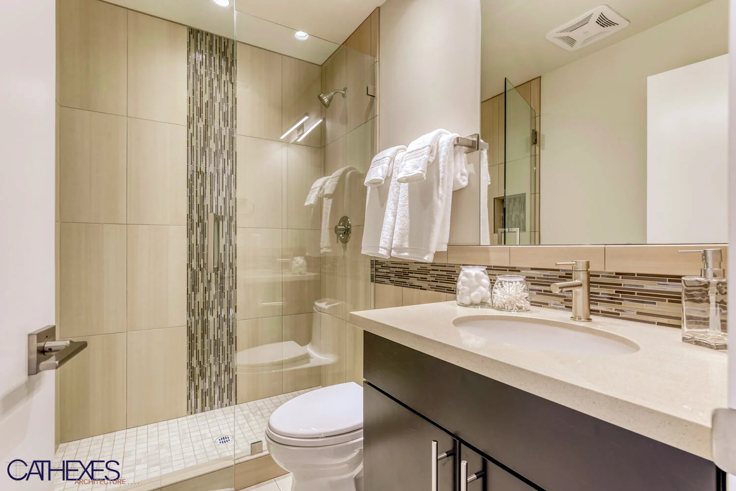 Bathroom with a glass shower, tall mosaic tile accent, and stone vanity