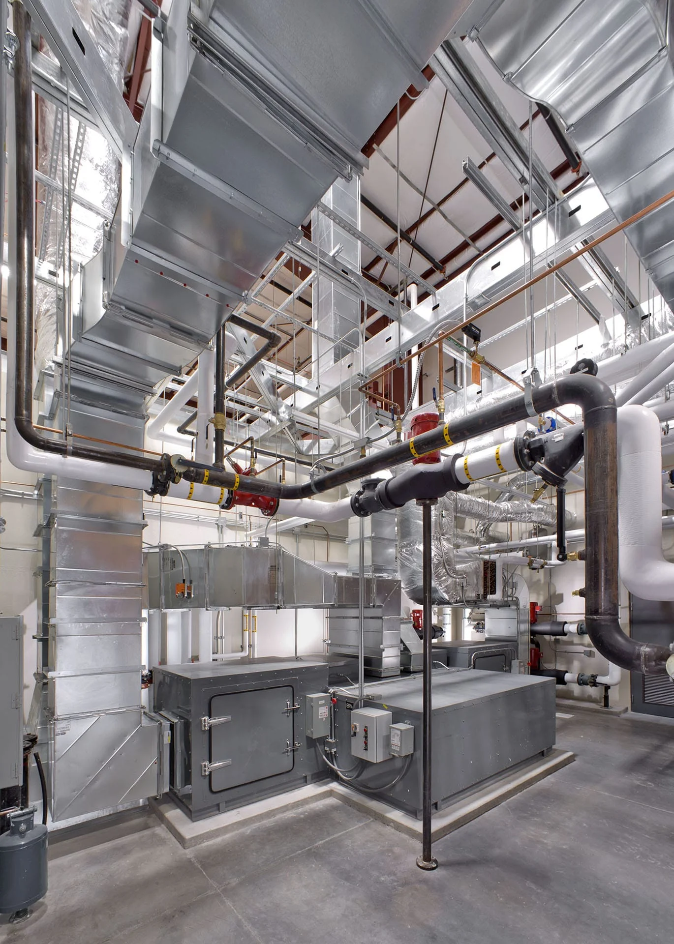 Mechanical room with exposed ductwork and ground-source heat pump equipment