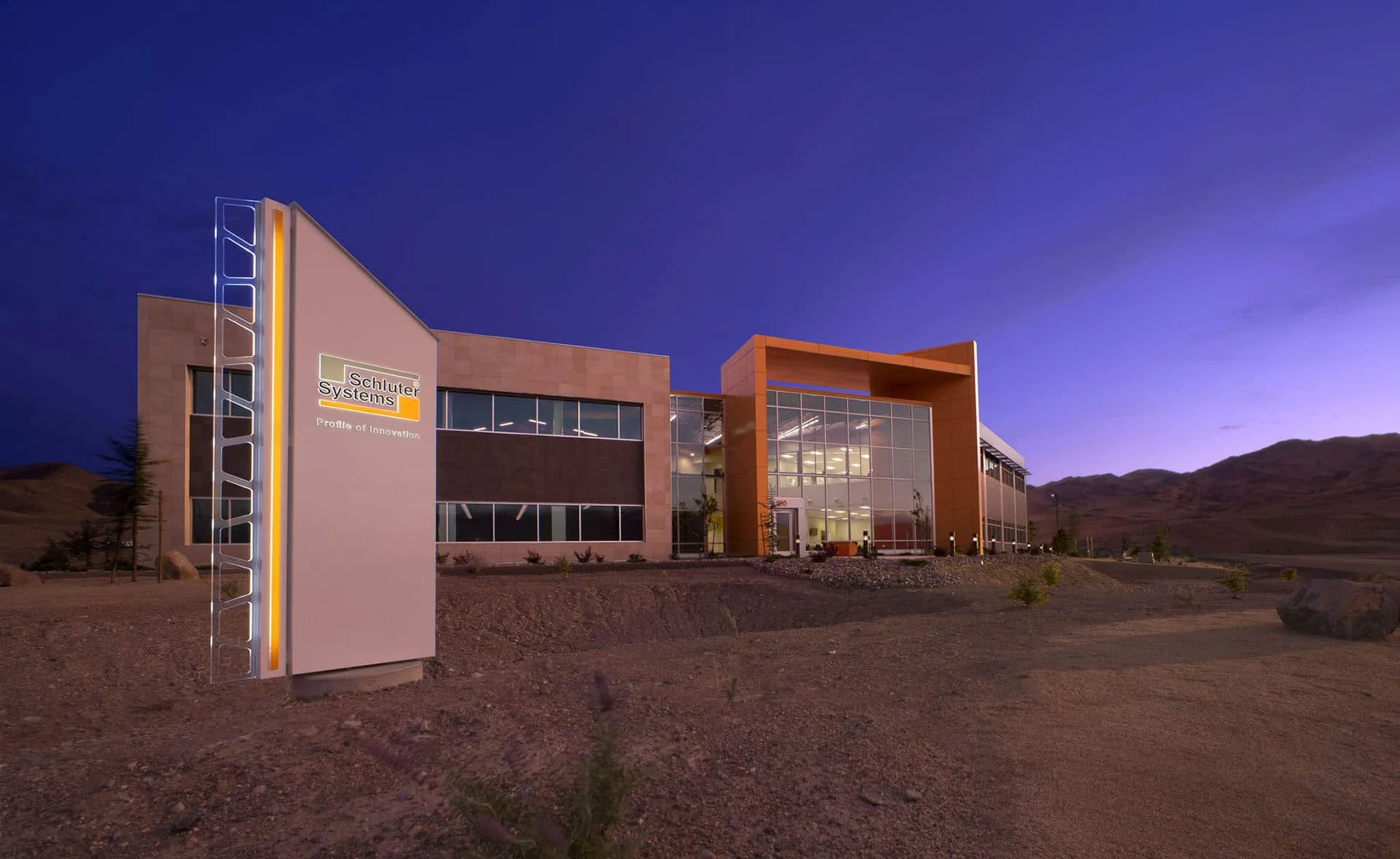 Schluter Systems monument sign and office building at dusk with mountains beyond