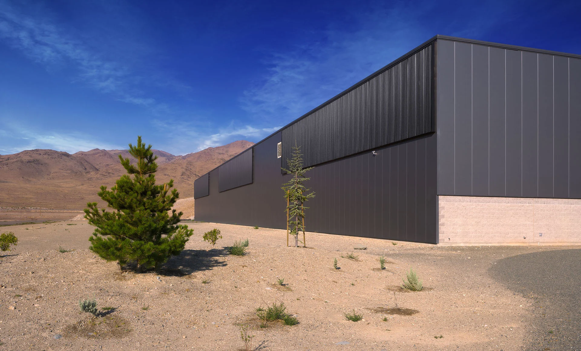 Long dark metal warehouse facade with a solar wall in the high desert