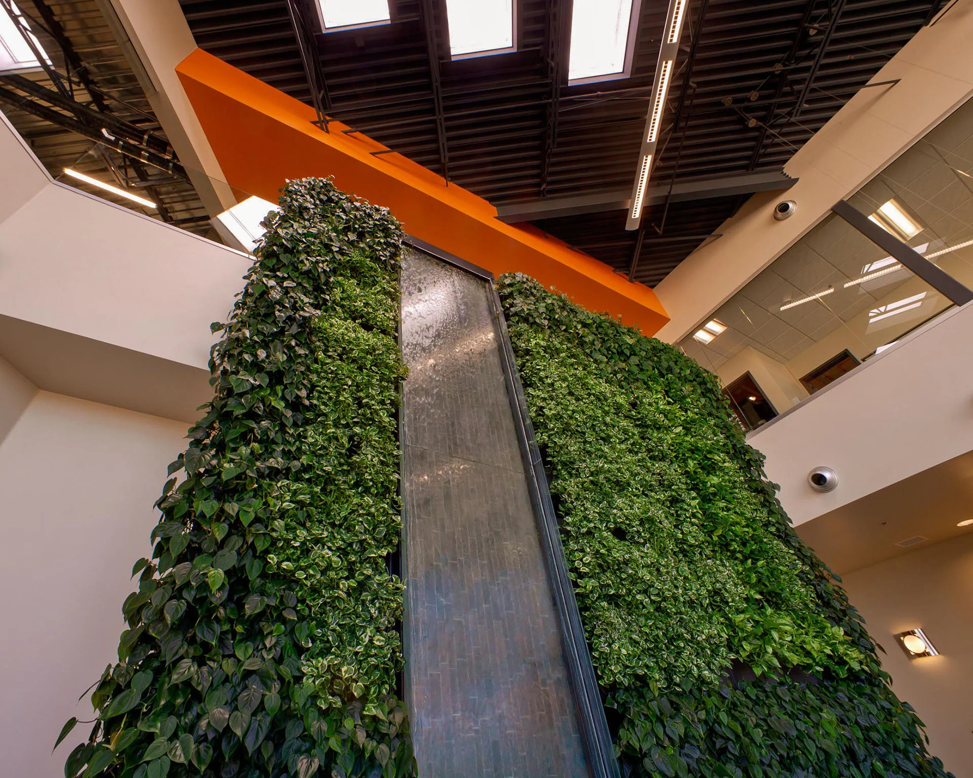 Multi-story living wall with a cascading water feature beneath an orange soffit
