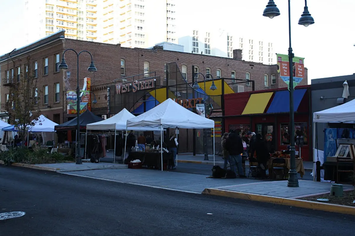 White vendor tents lining West Street in front of the historic brick market buildings