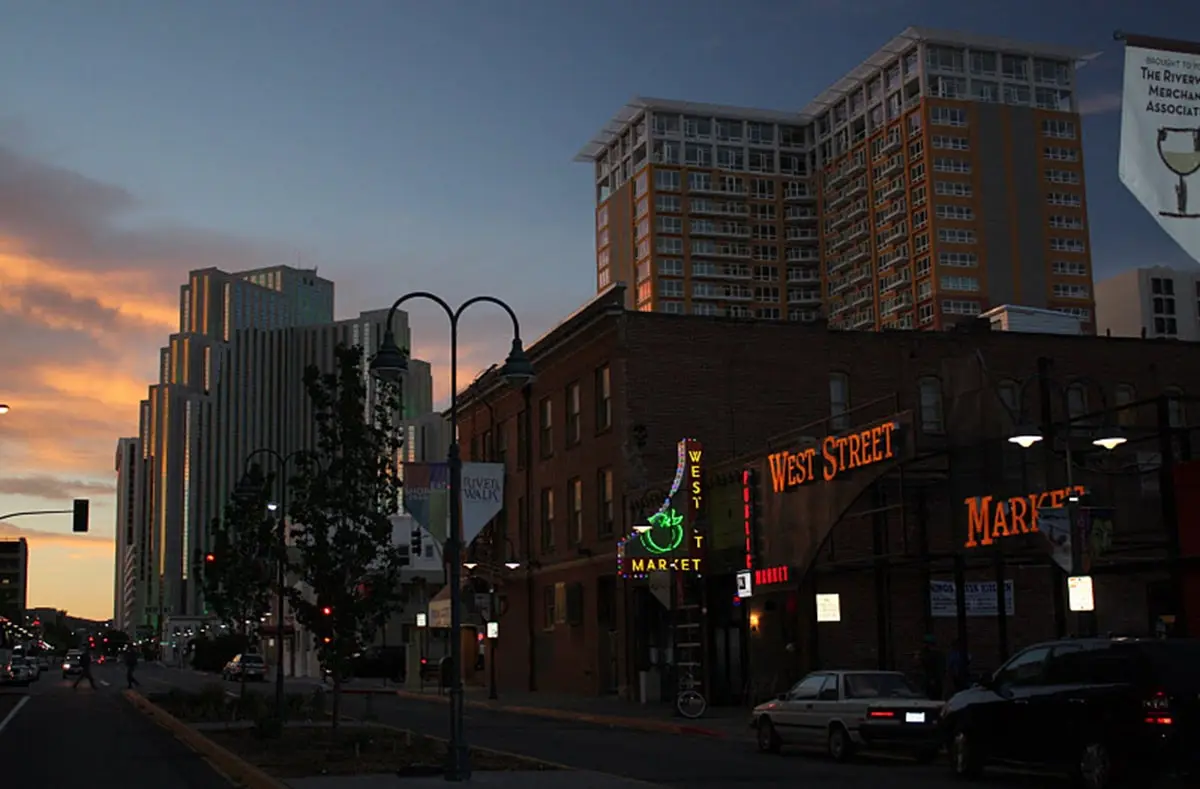 Historic brick West Street Market building at dusk with downtown Reno towers behind