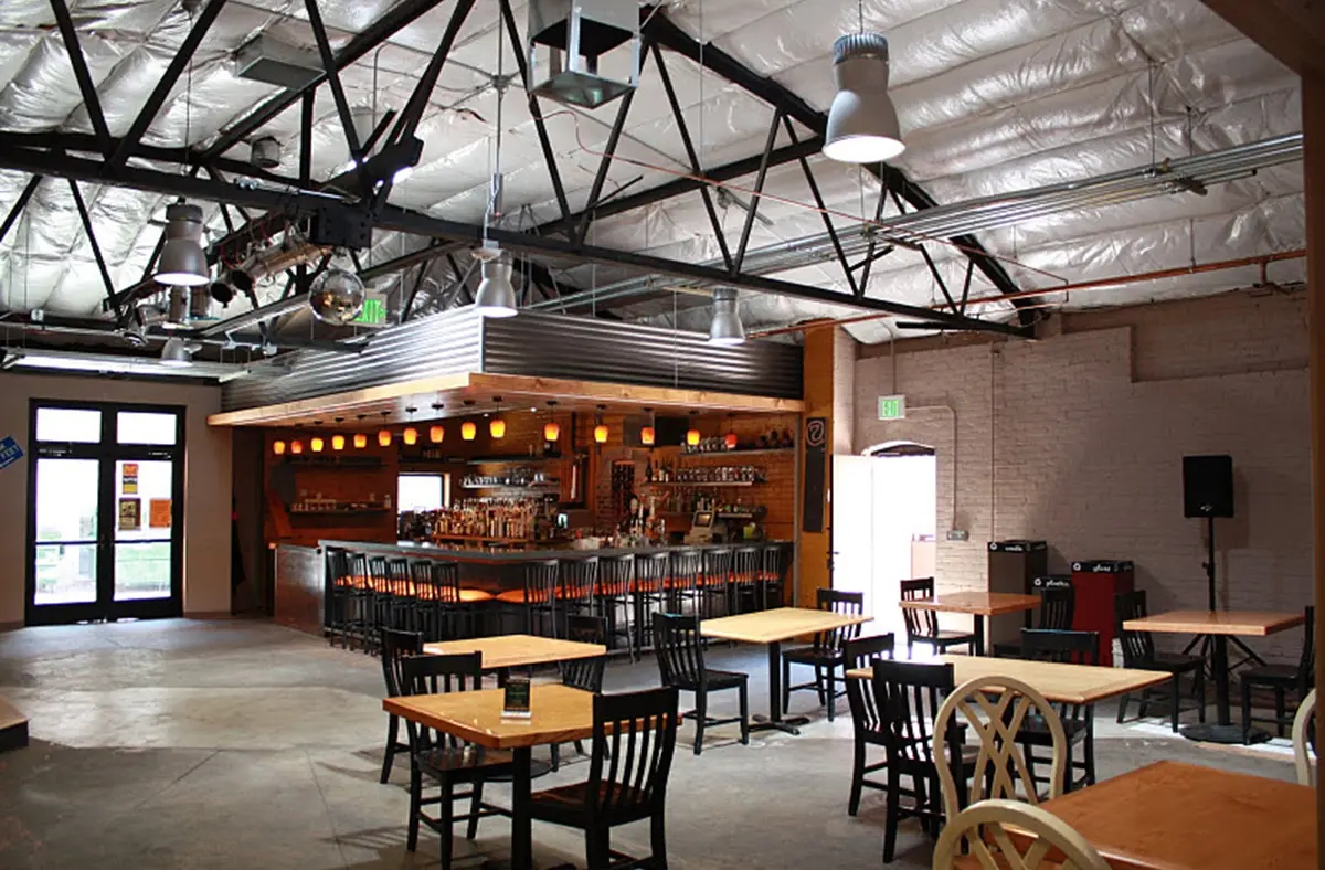 Restaurant bar and dining tables under exposed steel trusses in the renovated market building